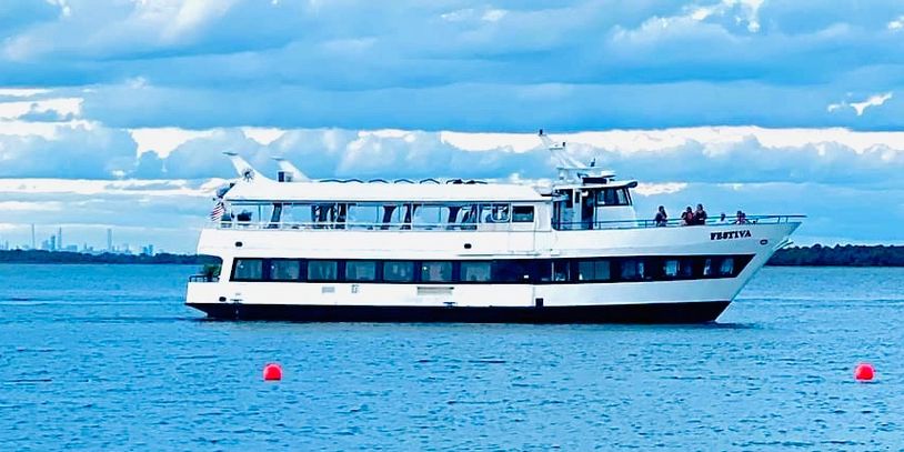 The Festiva yacht cruising past the beach bayfront in Highlands, New Jersey 