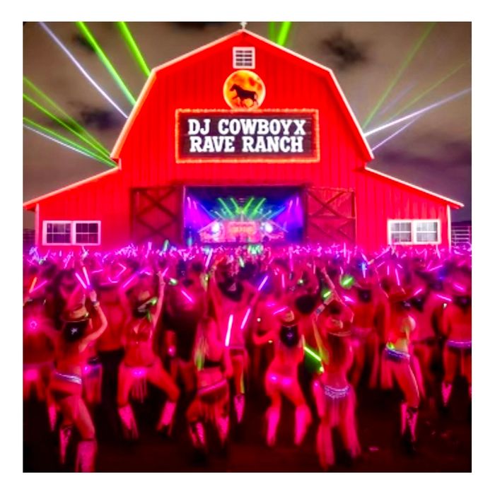 Crowd dancing with neon lights at DJ CowboyX Rave Ranch in a lit-up barn.