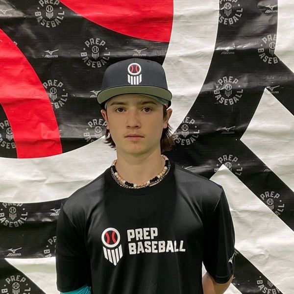 Young baseball player in Prep Baseball attire standing before a branded backdrop.
