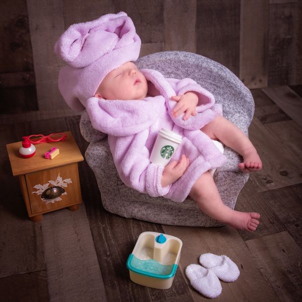 sleeping newborn girl holding coffee cup with slippers and robe