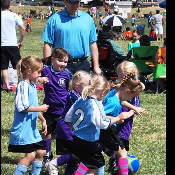 Young girls playing soccer with enthusiasm on a sunny day.