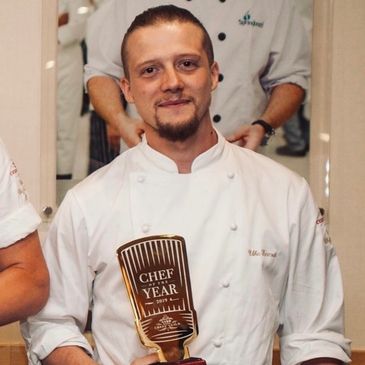 Chef proudly holding a 'Chef of the Year' award.