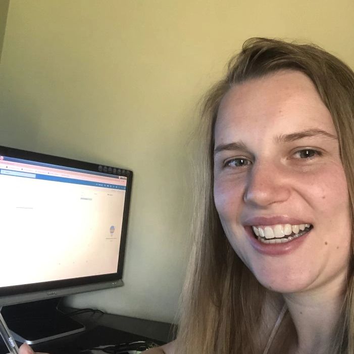 A young woman smiling at her computer workspace.