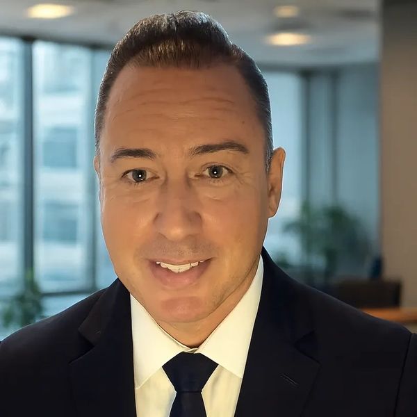 Professional man in a suit smiling indoors with office background.