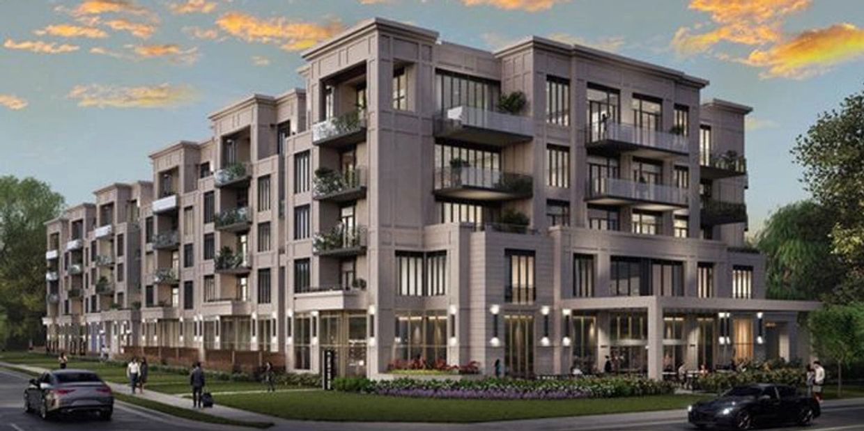 Modern four-story apartment building with balconies and greenery at sunset.