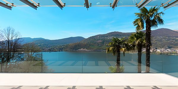 Deck com uma vista praiana ensolarada e um guarda-corpo em vidro sem perfis e cobertura de vidro.