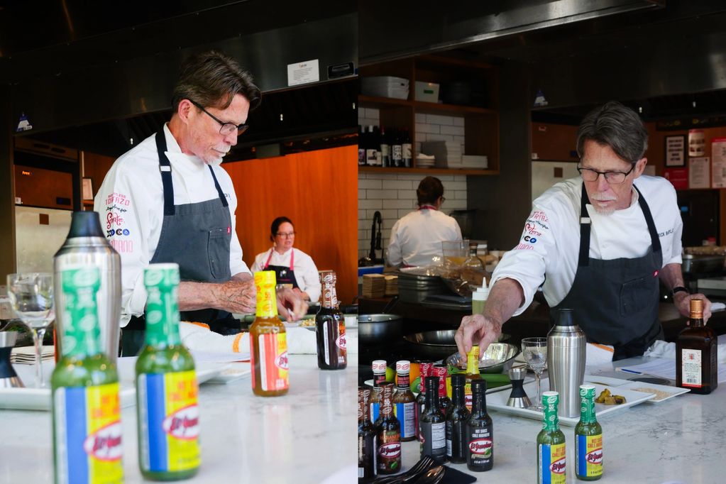 Chef in black apron preparing ingredients with various sauces on the counter.