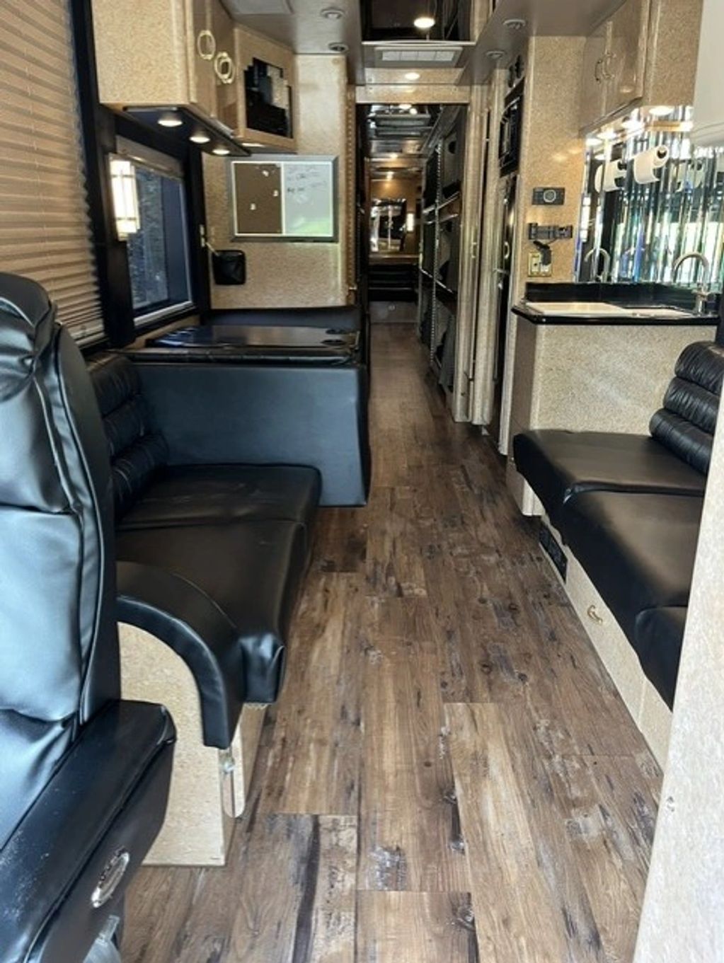 Interior view of a modern RV with leather seating and wooden flooring.