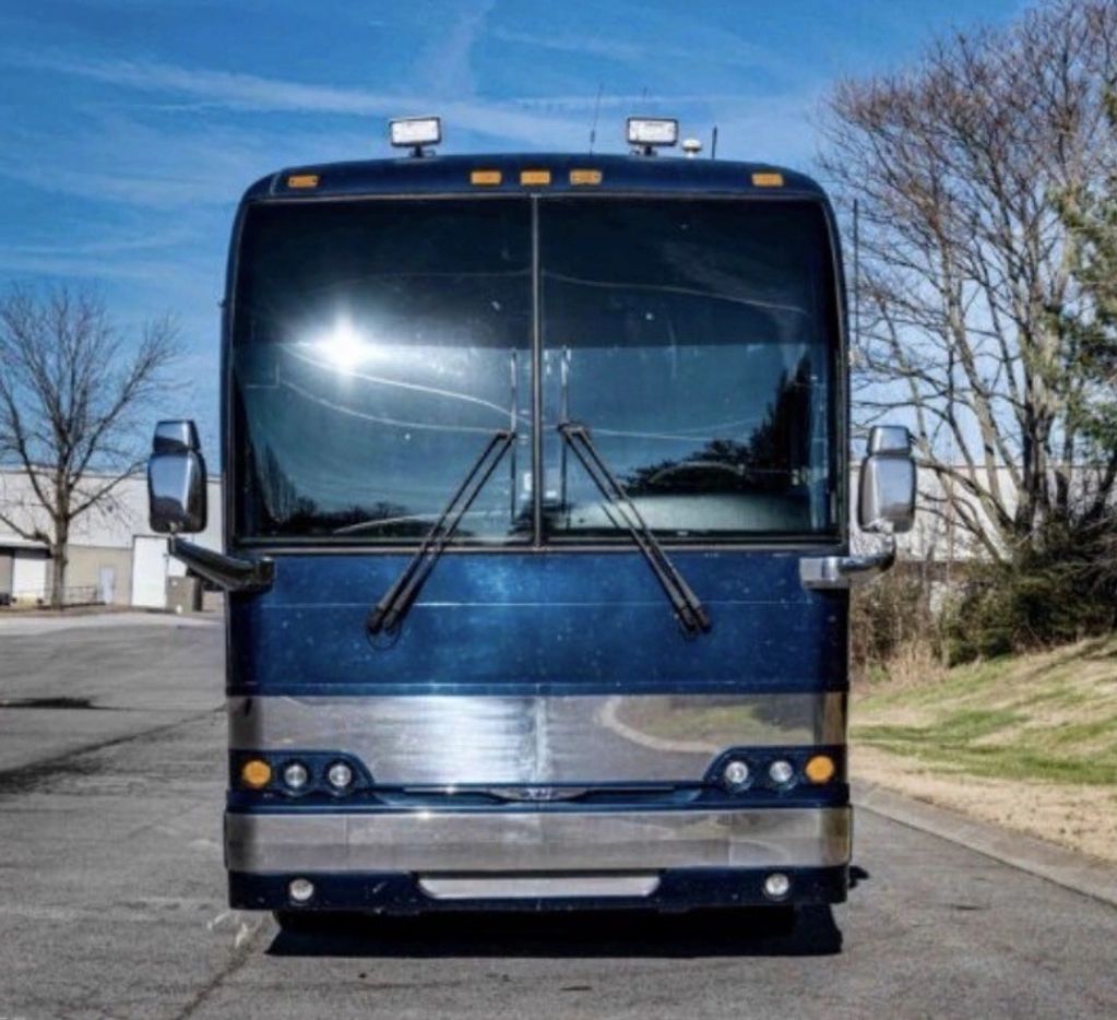 Front view of a blue and silver bus on a sunny day.