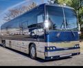 A sleek, blue luxury coach bus parked on a sunny street.