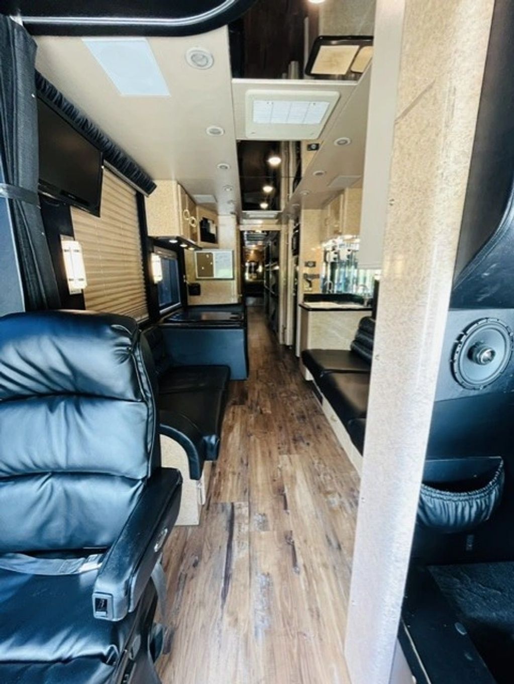 Interior of a luxurious bus featuring leather seats and wood flooring.