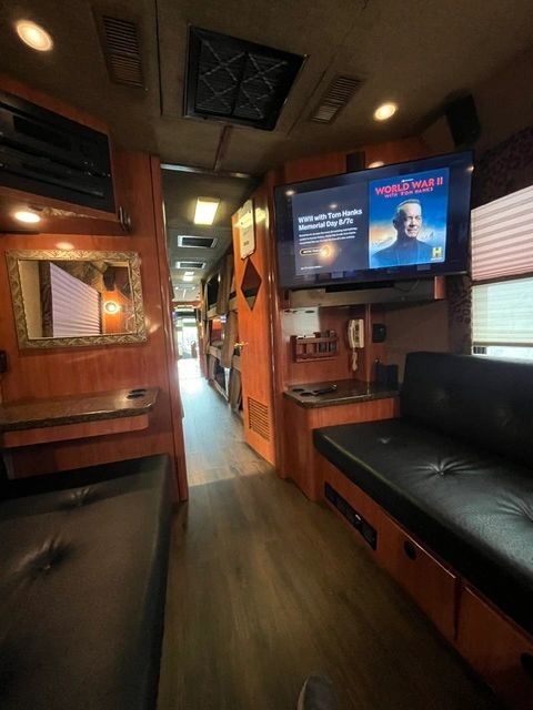 Cozy interior of a motorhome with wood paneling and a TV showing a WWII documentary.