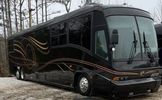 A sleek black luxury motorhome parked on a snowy driveway.