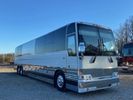 A sleek silver tour bus parked under a clear blue sky.