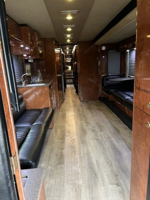 Interior of a spacious, modern RV with leather seating and wood finishes.