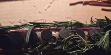 Close-up of a guitar neck with rosemary sprigs laid on top.