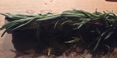 Fresh rosemary sprig on a wooden surface.