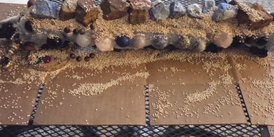 A row of ceramic pots with seeds scattered on cardboard below them.