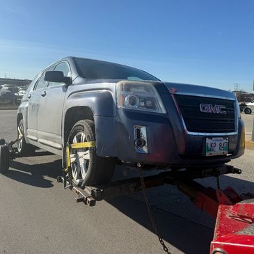 GMC vehicle on a tow truck at a clear sky day.