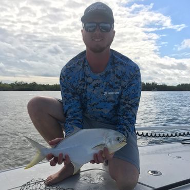 Man holding pompano while fishing on a boat