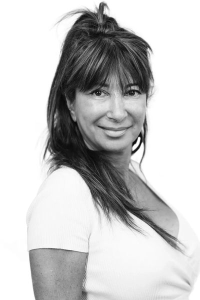 Black and white portrait of a smiling woman with long hair and bangs.