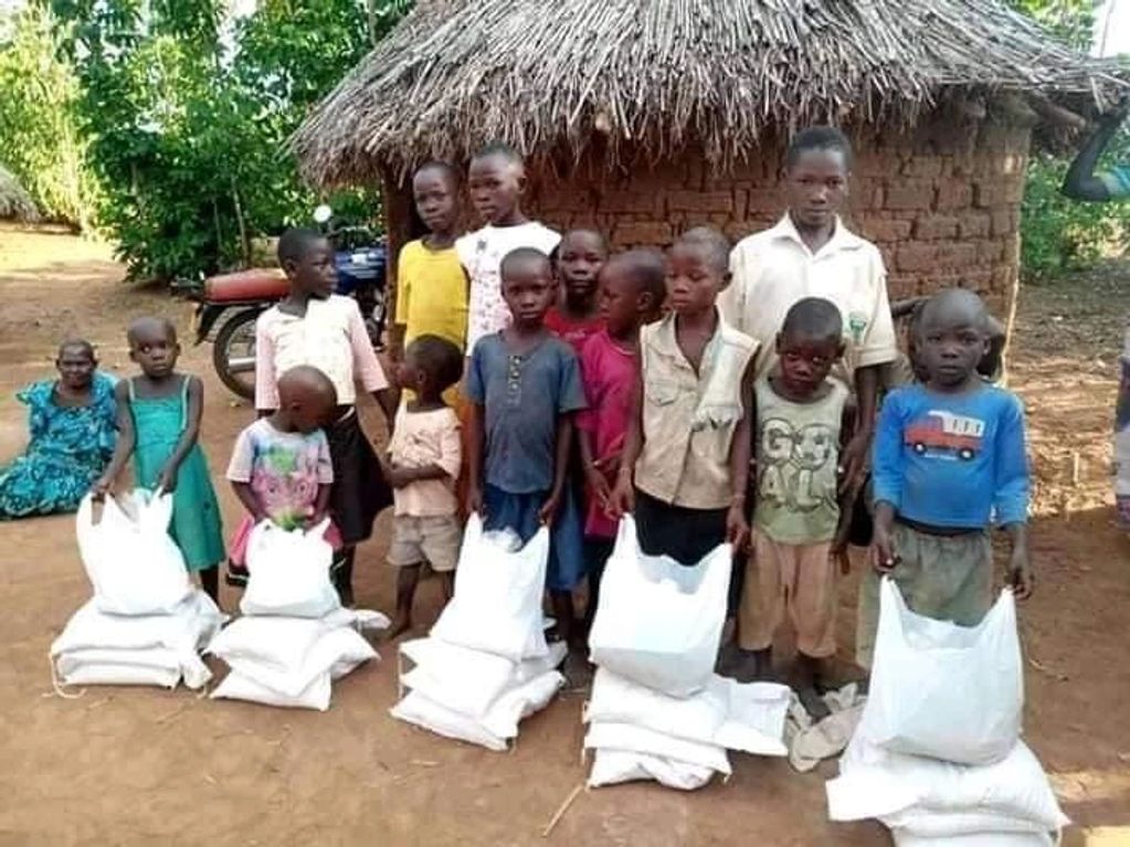 Children standing in a line with bags of supplies outdoors.