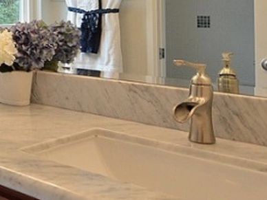 Modern bathroom with marble countertop and wooden cabinets.
