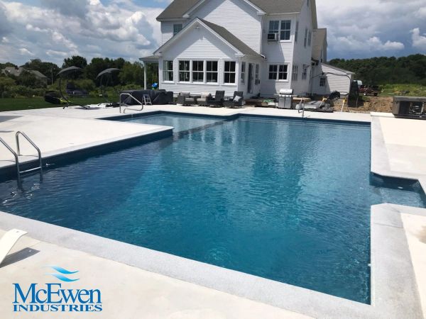 A clear blue swimming pool in front of a white house.