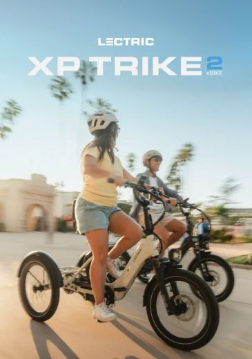 Two people riding Lectric XP Trike 2 e-bikes outdoors.