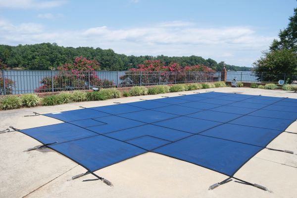 Pool covered with a blue safety cover on a sunny day.