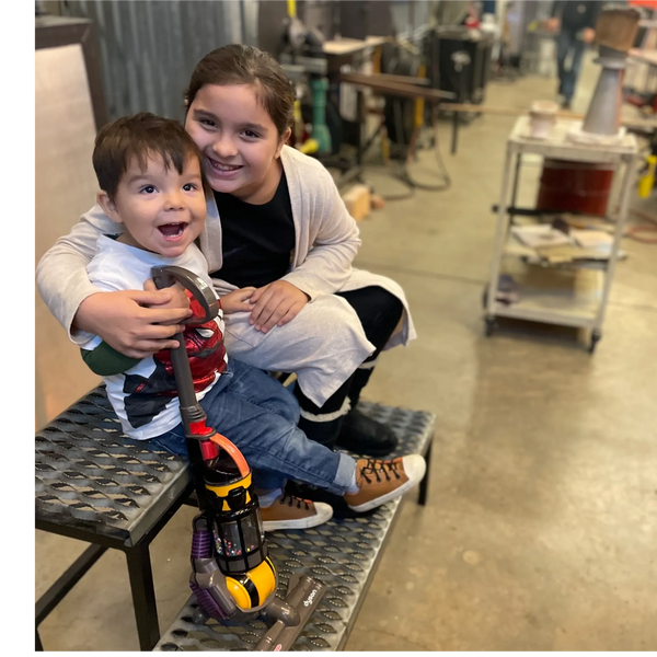 2 smiling kids in a hotshop.