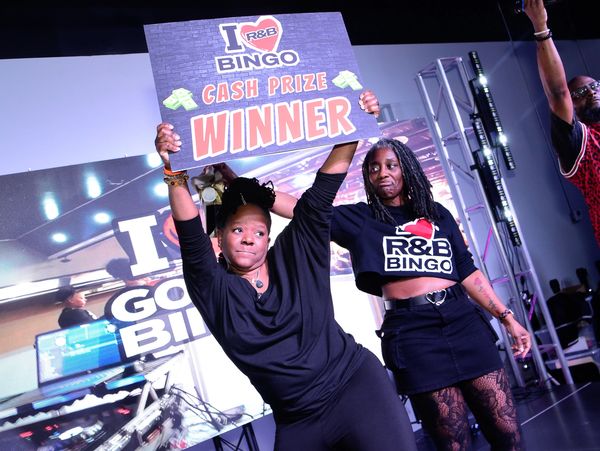 Woman holding winner sign for R&amp;B Bingo cash prize.