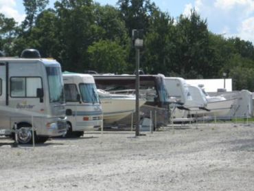 Parked RVs and boats at a storage lot.