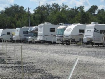 A row of RVs parked on a gravel lot.