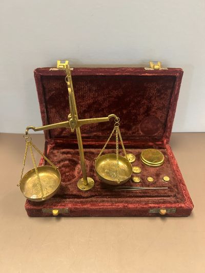 Antique brass balance scale set in a red velvet case.