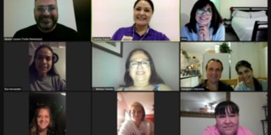 A virtual meeting with nine smiling participants on a video call.