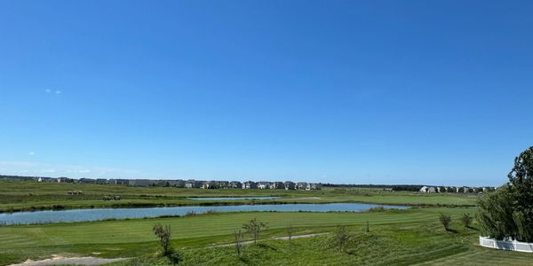 Wide landscape with a river, green fields, and clear blue sky.