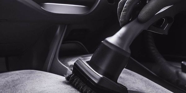 Black and grey themed picture of a car being vacuumed