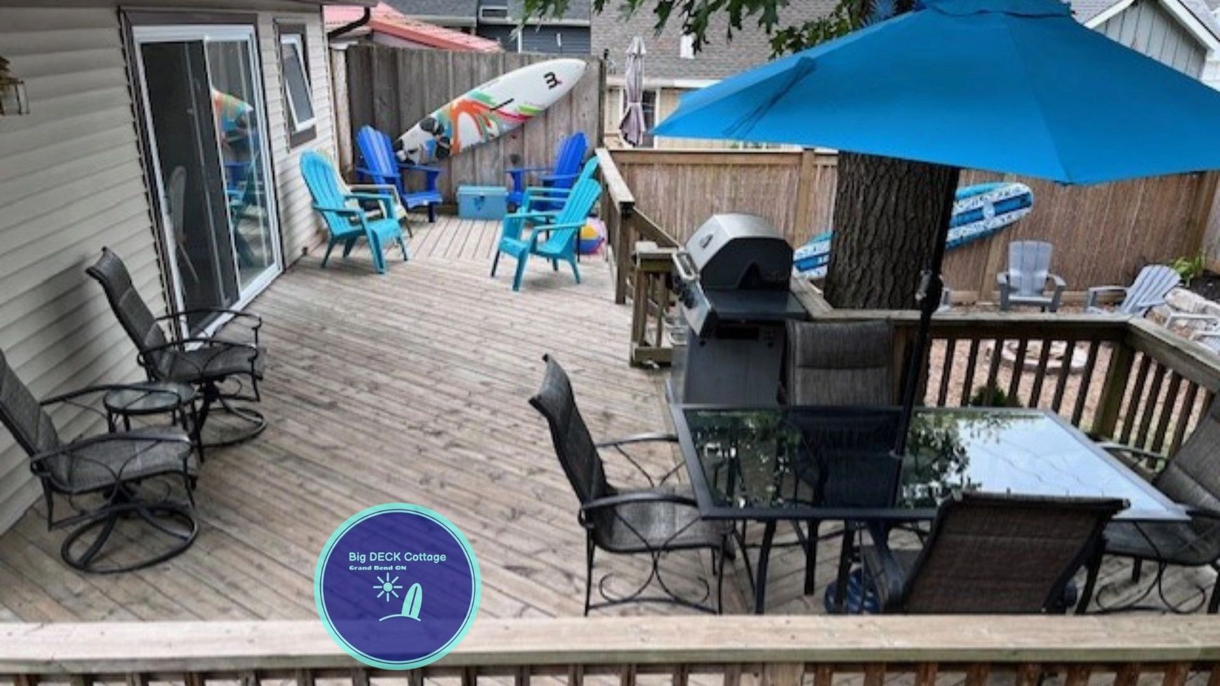 Spacious wooden deck with seating, grill, and surfboards for a relaxing outdoor experience.