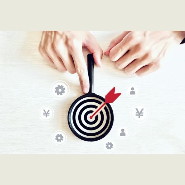 Hands pointing at a dart hitting the bullseye on a target with business icons around.
