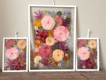 Three framed floral artworks with pink, orange, purple flowers.