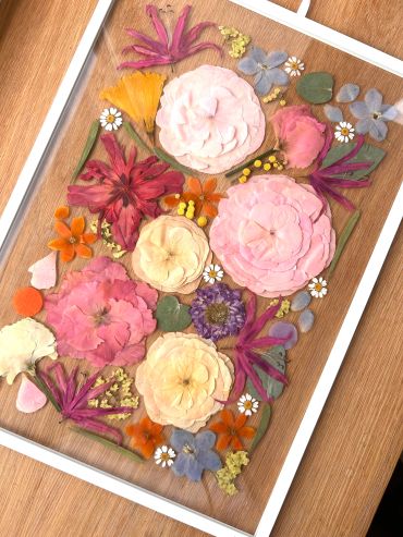 Pressed flower art in a frame on wood.