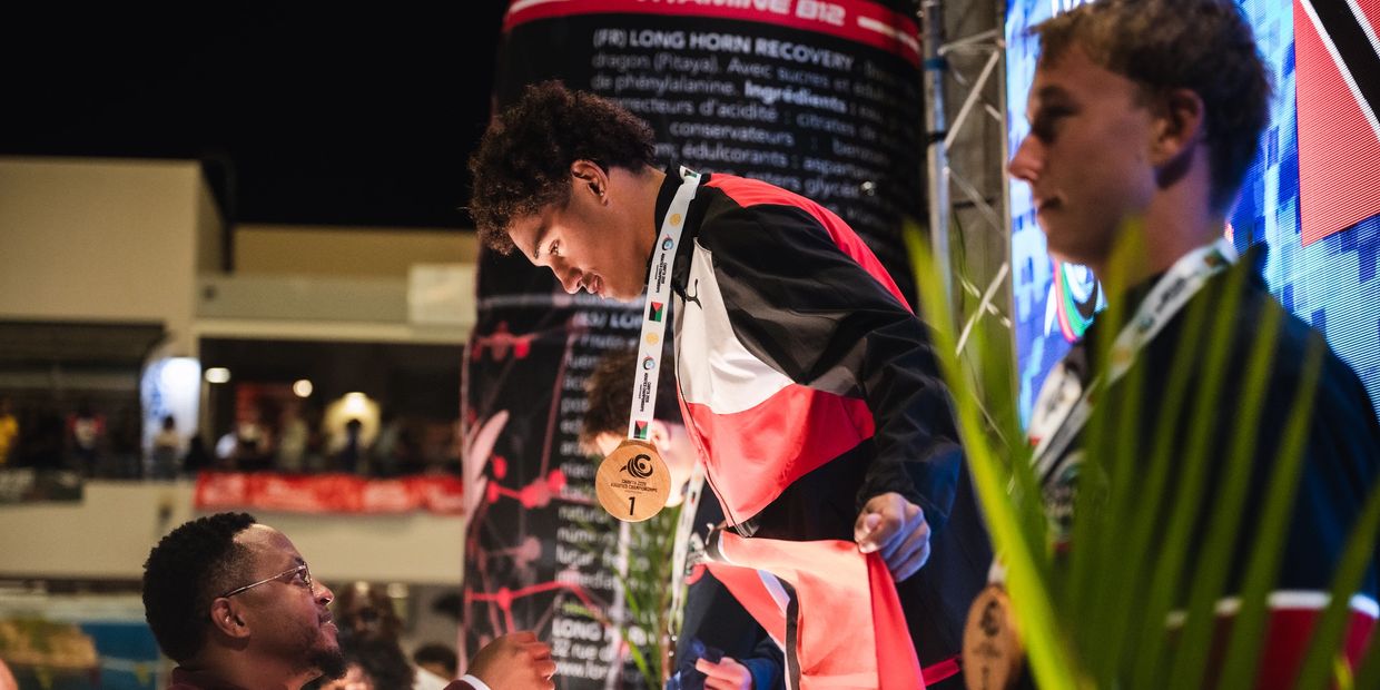 Athlete receiving a gold medal on the podium at a nighttime event.
