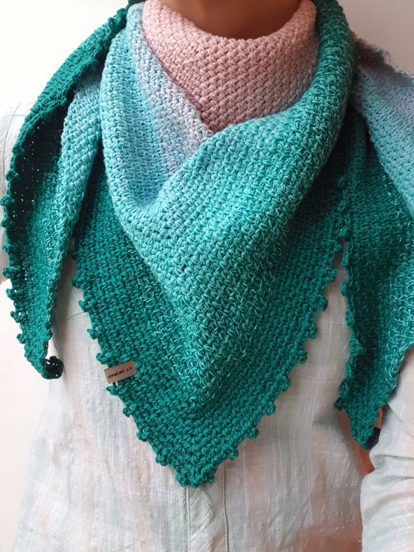 Person wearing a green and pink knitted shawl.