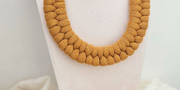 Chunky mustard yellow knitted necklace on display.