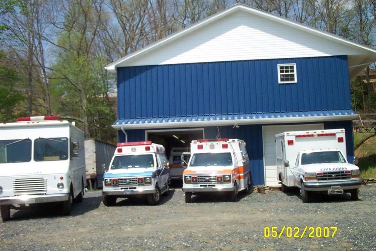 Four ambulances parked outside a blue emergency services building.