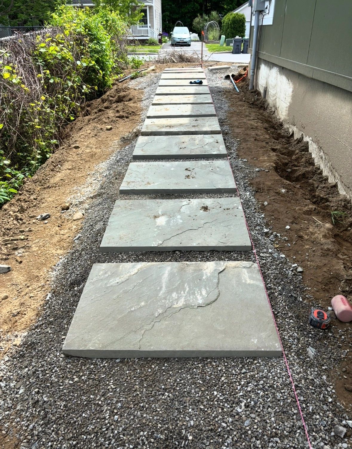 Newly installed stone pathway with rectangular slabs on gravel base.