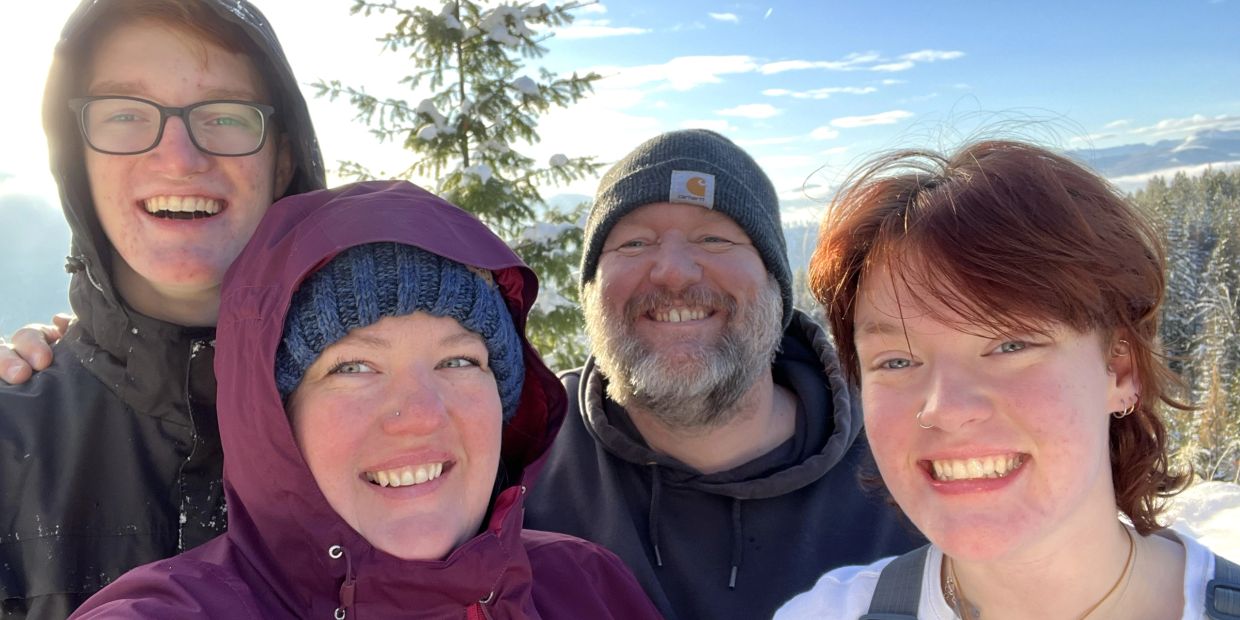 A happy family smiling outdoors on a sunny winter day.