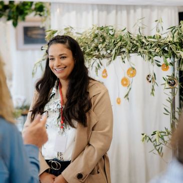 Smiling woman in a beige coat at an event.