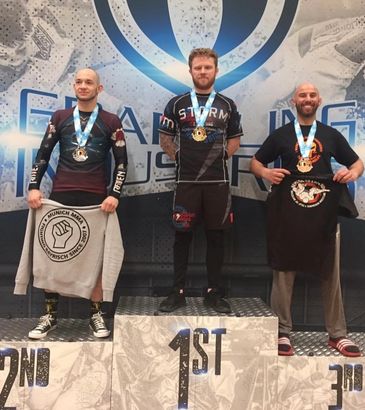 Three men on a winners' podium with medals.